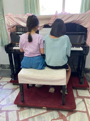 玥爾音樂工作室 - 週六假日鋼琴社團課，上課時
學生兩兩坐在鋼琴前面練習
（圖中兩位孩子均為小學四年級）