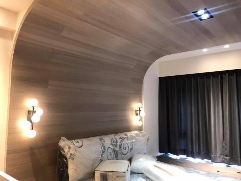 VergilWang - 床頭背板的木皮拼接圓弧延伸至天花板，圓滑較不死硬的修飾床頭上方的結構樑