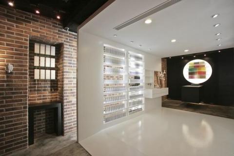 築合室內裝修設計有限公司 - 來自紐約流行化妝品牌進駐台北東區，首間概念店落腳敦化商圈人潮聚集地，在設計上我們延續了紐約店型風格，以復古磚、水泥粉光、epoxy塗料、噴漆呈現出復古時尚氛圍，入口處的公仔擺飾與壁面手部道具及黑鐵框架，為產品增添些許趣味性，中段走道以白色框架形式塑造過渡空間，並巧妙的隱藏商品兩側間接燈光與工作空間，端景圓形壁面展示了色彩豐富的包裝商品，黑白反差加大了空間景深效果，解決了空間坪數不足的問題！