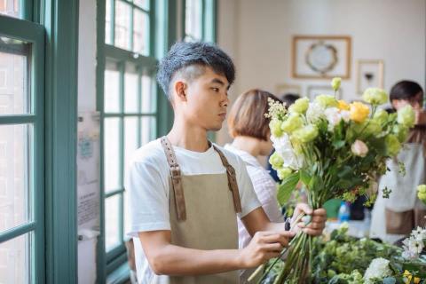 FR花想世界 - 藝材料相當多元，包括了鮮 花、水果、蔬菜和其他特殊媒材，也擅於將 花藝與異材質碰撞融合，注入當代創意、以 幾近概念藝術般的非常規方式，打造介於花 藝和裝置藝術之間的作品。