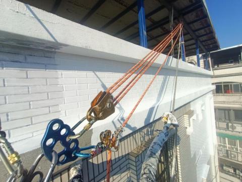 新立外牆繩索工程 - 一噴洗三塗層的防水漆施工（照片中是二塗層施工中）