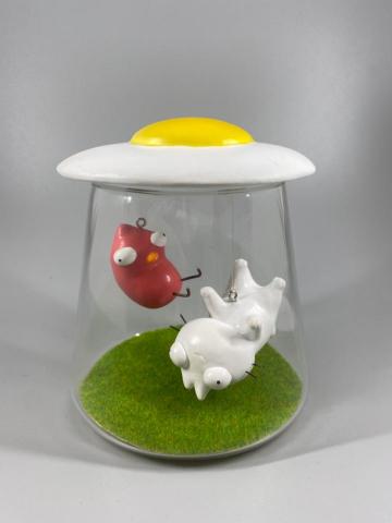 廖翊庭 - 與好的小安插畫家聯名的平面立體畫作品，以玻璃杯創造小安及小雞被荷包蛋幽浮吸走的畫面，製作從雕塑/塗裝及懸掛技巧皆由鯊舟工作室製作。