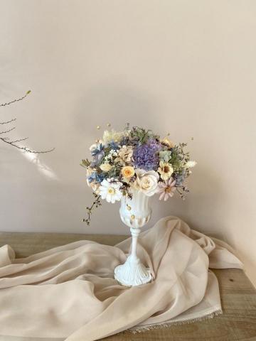 植感物語 - 改良式的畢德麥爾桌花,可以360度欣賞;配上白色高腳冠軍盃,將盆花襯托得更加精緻高雅。本作品採用的花材包括玫瑰、康乃馨、木片瑪格麗特、木片銀蓮花、佳那利、罌粟果、小百日草、卡斯比亞、法國白梅、繡球、尤加利果實、香桃木、臨花….等十多種不凋花暨乾燥花,造型復古、色調清新、緊密間留有空氣感,為室內一隅帶來生動的靈氣。 植感物語 - 改良式的畢德麥爾桌花,可以360度欣賞;配上白色高腳冠軍盃,將盆花襯托得更加精緻高雅。本作品採用的花材包括玫瑰、康乃馨、木片瑪格麗特、木片銀蓮花、佳那利、罌粟果、小百日草、卡斯比亞、法國白梅、繡球、尤加利果實、香桃木、臨花….等十多種不凋花暨乾燥花,造型復古、色調清新、緊密間留有空氣感,為室內一隅帶來生動的靈氣。