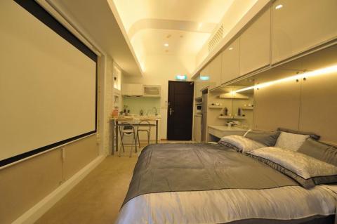 老屋翻新及浴室翻新設計施工團隊 - 使用投影機功能的電視劇院組合，使用地毯與瓷磚分割室內外空間，並設計化妝台以及床邊多功能儲櫃跟衣櫃，並有兩人式餐桌，並在天花板設置空調與照明，讓空間變得挑高與溫馨。
