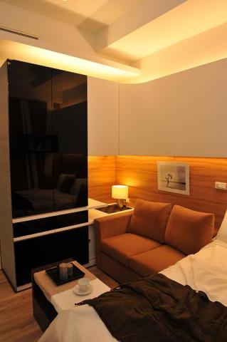 老屋翻新及浴室翻新設計施工團隊 - 毛胚屋，小套房設計，使用玻璃作為衣櫃面板，並使用木工工法在牆面展示間接照明，並訂製適合家具，營造現代溫暖的氛圍。