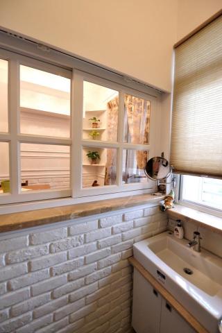 老屋翻新及浴室翻新設計施工團隊 - 衛浴牆面貼附文化石，並在上方設計窗戶讓視野可以通透，有訪客時可以將捲簾拉下，並有暖風機與窗戶流通，浴室很快就乾式不會潮濕。