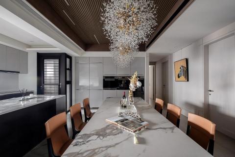 沐見設計室內裝修有限公司 - 仿石紋的薄板磚桌面耐用典雅，
與橘色餐椅呈現典雅氣質；深色木皮的天空線映照璀璨星星般的吊燈，整個餐廳變得更溫暖
