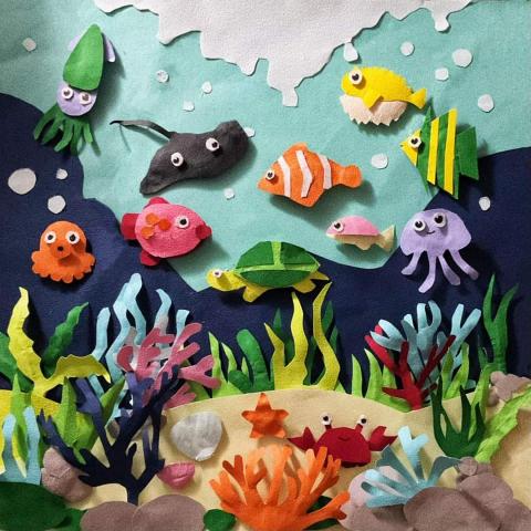 優優(yoyo) - 《海底奇境》
紙雕手工作品展現了充滿生命的海底世界，眾多魚群在珊瑚和海草間穿梭，搭配小石頭營造出自然真實的海洋景觀，細緻的雕刻和巧妙的佈局讓這幅作品充滿了活力和細節，仿佛將觀者帶入一個美麗而神秘的海底奇境