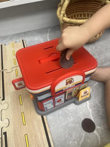 蜻蜓陪玩/陪讀 - 每次陪玩除了運用寶貝家中的教玩具，我也會準備一些自己的教具，除了增加孩子的興趣，也讓寶貝們有不同的刺激，圖中的教玩具，提供寶貝手眼協調、專注力、耐心、挫折容忍力及手部精細動作等能力培養，是很好的遊戲活動，1-3歲的孩子喜歡重複性遊戲活動/行為，透過重複的投硬幣、紙鈔並將其拿出來，孩子會非常有興趣，甚至年齡增長，可加入金錢、儲蓄觀念，即早建立孩子儲蓄觀念，一起探討「想要和需要」。