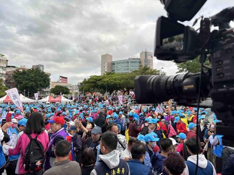 新點子錄影 - 【淡水捷運站造勢現場｜在人群與海風之間切畫面】

今天在淡水捷運站旁、黃金海岸步道一帶進行選舉造勢活動拍攝。這裡同時也是通往淡水老街的步行動線，平日是遊客散步看海的地方，今天則被滿滿的人潮與旗幟填滿，氣氛熱鬧又有力量。

導播台架設完成後，眼前是一片藍帽人海，口號聲、音樂聲與現場主持的節奏交織在一起。攝影機不斷捕捉群眾互動、揮旗吶喊與舞台上的每個關鍵瞬間，畫面切換之間，要兼顧情緒、節奏與現場氛圍，讓觀眾透過螢幕也能感受到現場的熱度。

有趣的是，工作地點就在海風與河岸景色旁。抬頭是灰雲層次分明的天空，遠方
