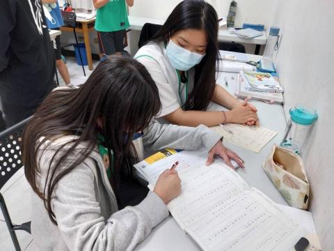 陳琪惠 - 此圖是台中市沐風關懷協會擔任志工的照片，於沐風擔任志工已9年經驗，我的主要任務是協助孩子完成課業並進行一對一解題。對我而言，這不只是檢查作業，更是一場「提供新邏輯思維」的過程。有些孩子面對困難題目會想放棄，我會運用 9 年累積的溝通技巧，提供新的方向與建議，引導他們一步步找到答案。我深知教育不僅是知識的傳遞，更是長期的陪伴。我希望將這份專業與熱忱，一步步陪伴孩子在學習路上穩步前行。